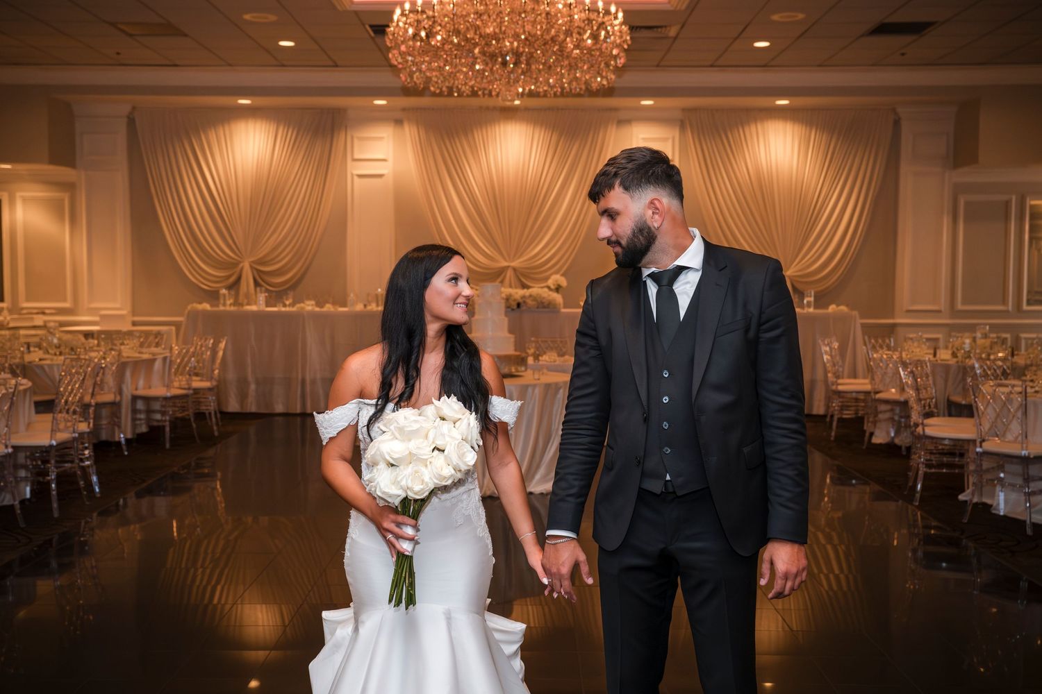 Elegant wedding reception venue with crystal chandeliers and draped fabric decor creating a romantic atmosphere.