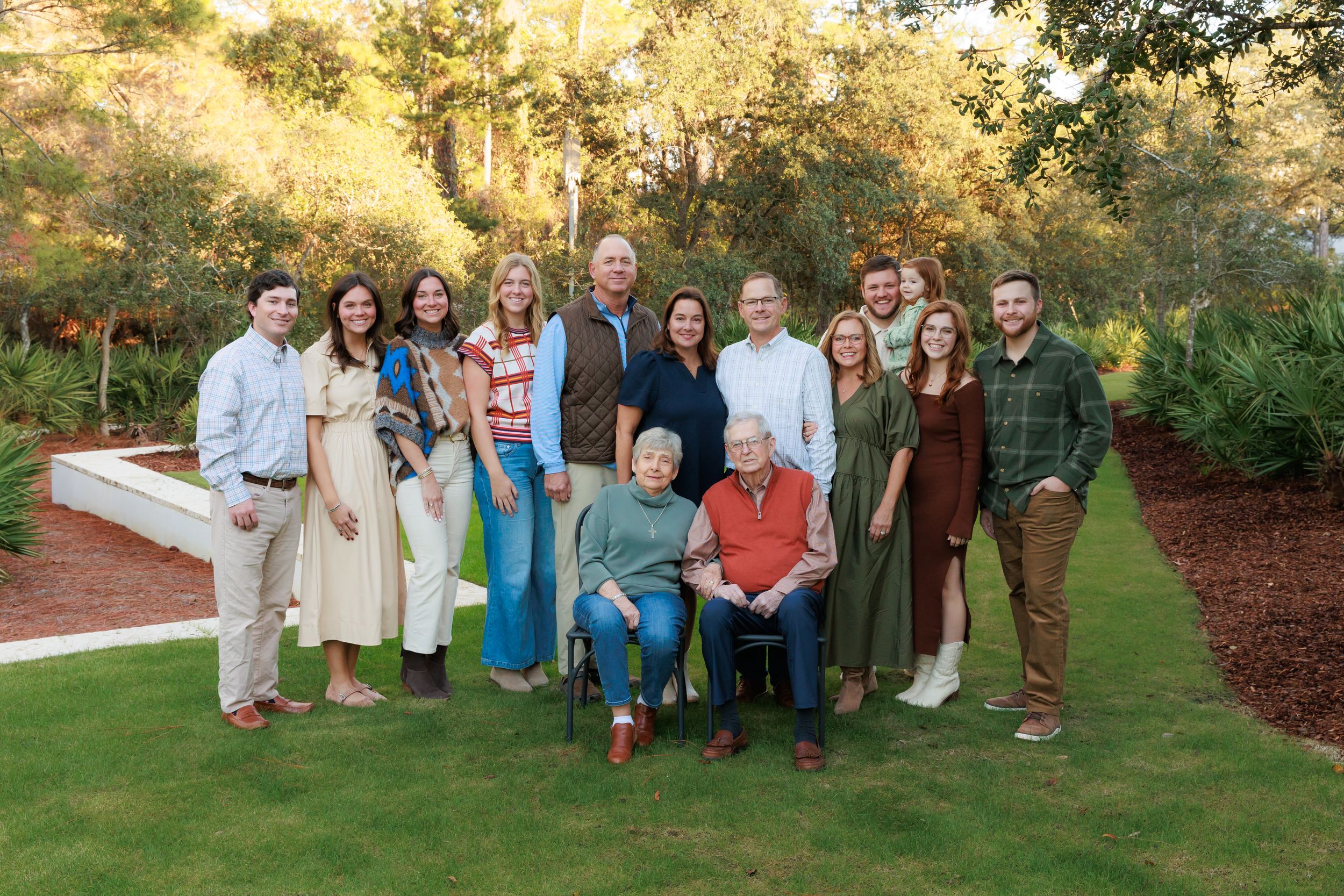 A collection of outdoor family portraits taken in a park setting with natural fall foliage in the background.