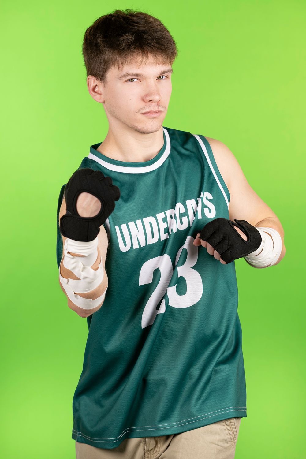 Athletic figure in green jersey number 23 poses with sports gear against bright background.