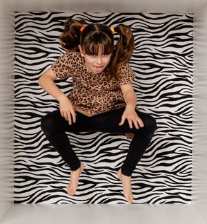 Person posing in a leopard print top against a black and white zebra striped backdrop.