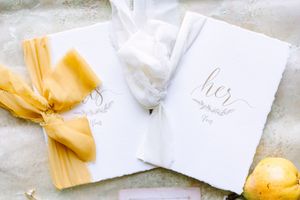 Elegant white invitations or cards tied with yellow ribbons arranged on a light marble surface.