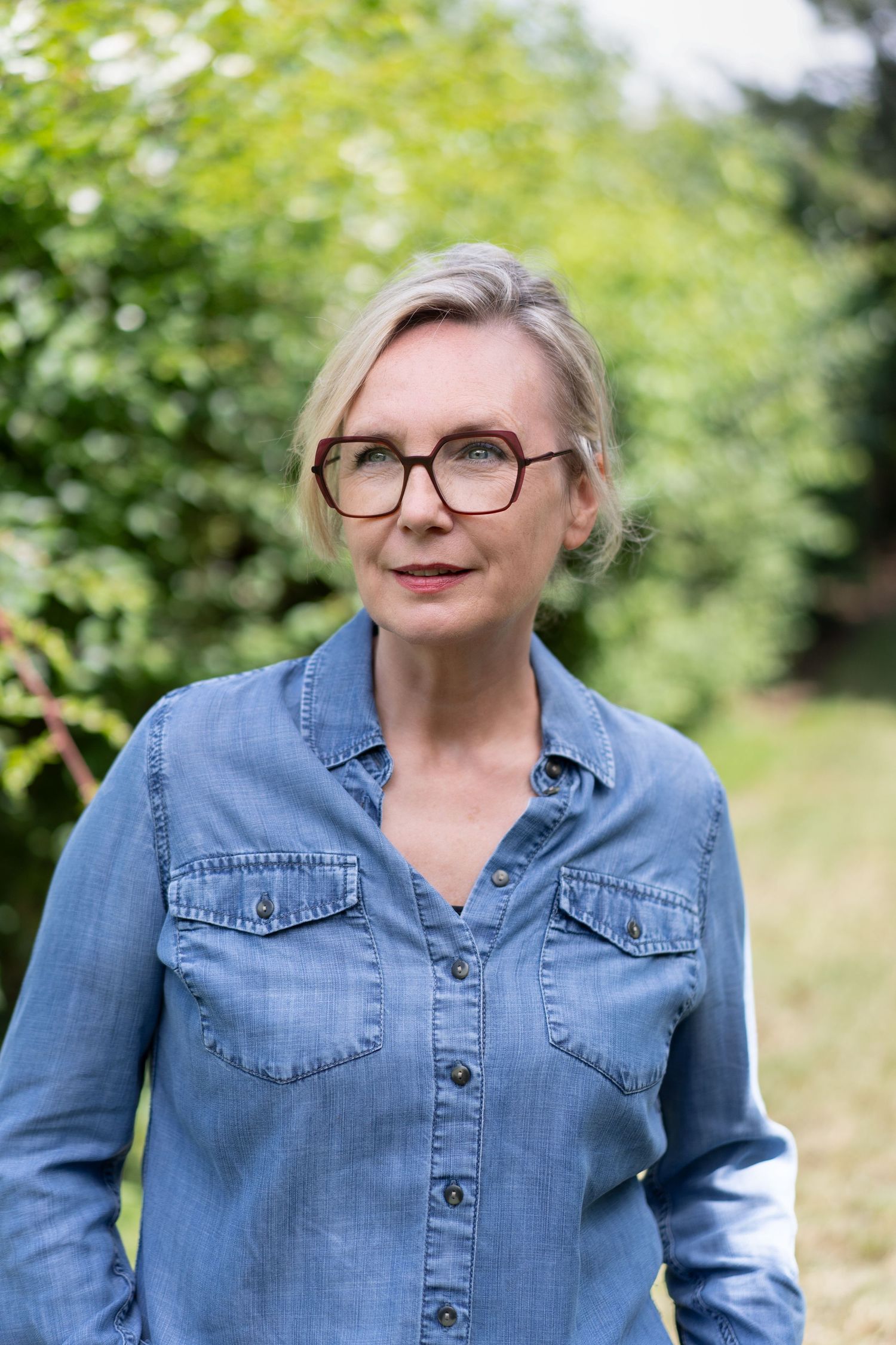 Female business leader personal branding photoshoot in Southsea, Portsmouth. She wears a denim shirt and dark red glasses.