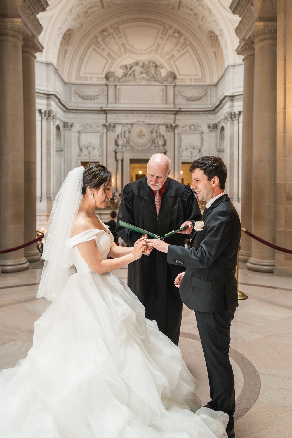 Wedding ceremony moments captured in an ornate marble hallway with elegant architectural details.