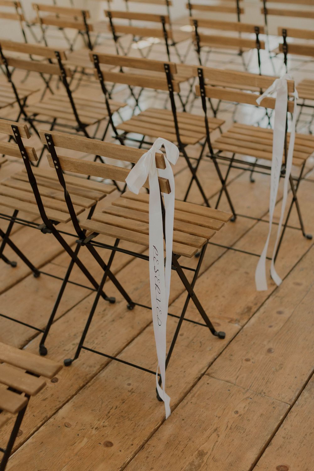 Rows of white folding chairs arranged on wooden floorboards for a ceremony.