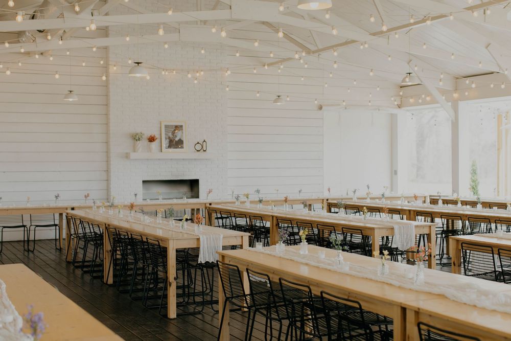 Long rows of wooden tables and chairs set up in a bright white reception hall.