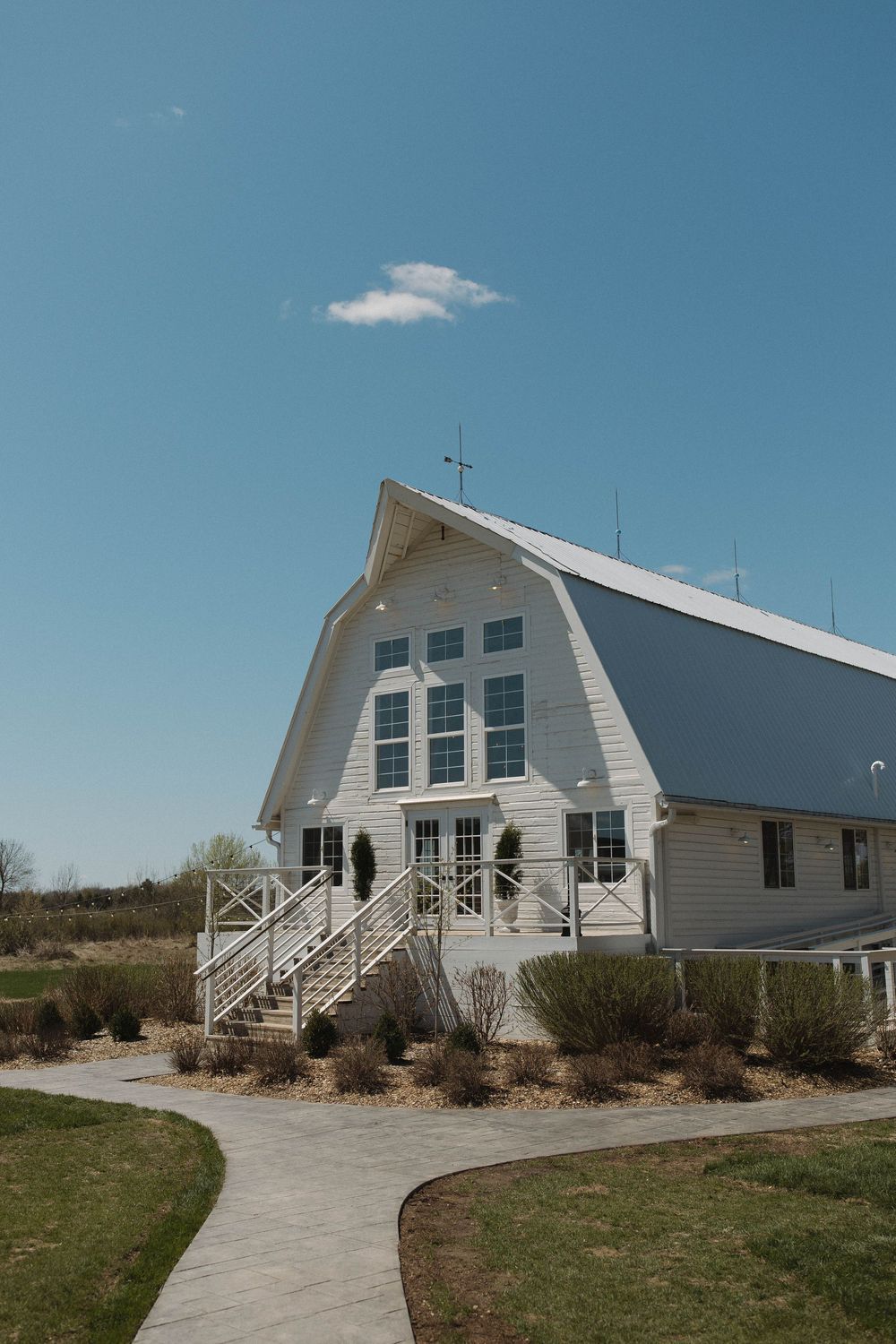 A white barn-style church building with gambrel roof and large windows against a blue sky.