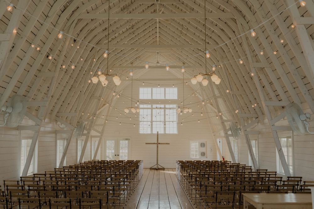 A vaulted ceiling with exposed wooden beams and string lights in an elegant event space.