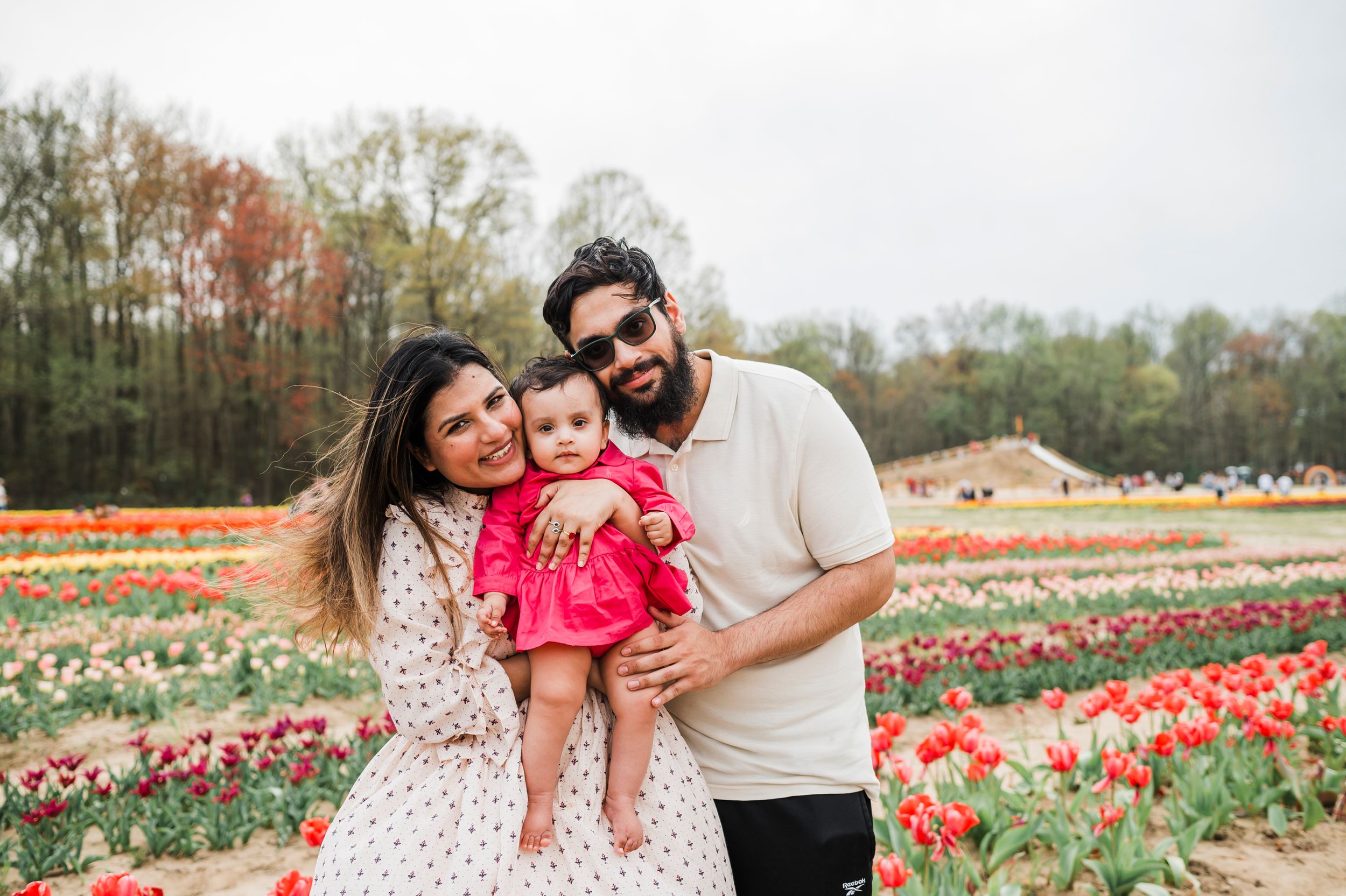 A loving family poses together among rows of vibrant tulips blooming in a field during springtime.