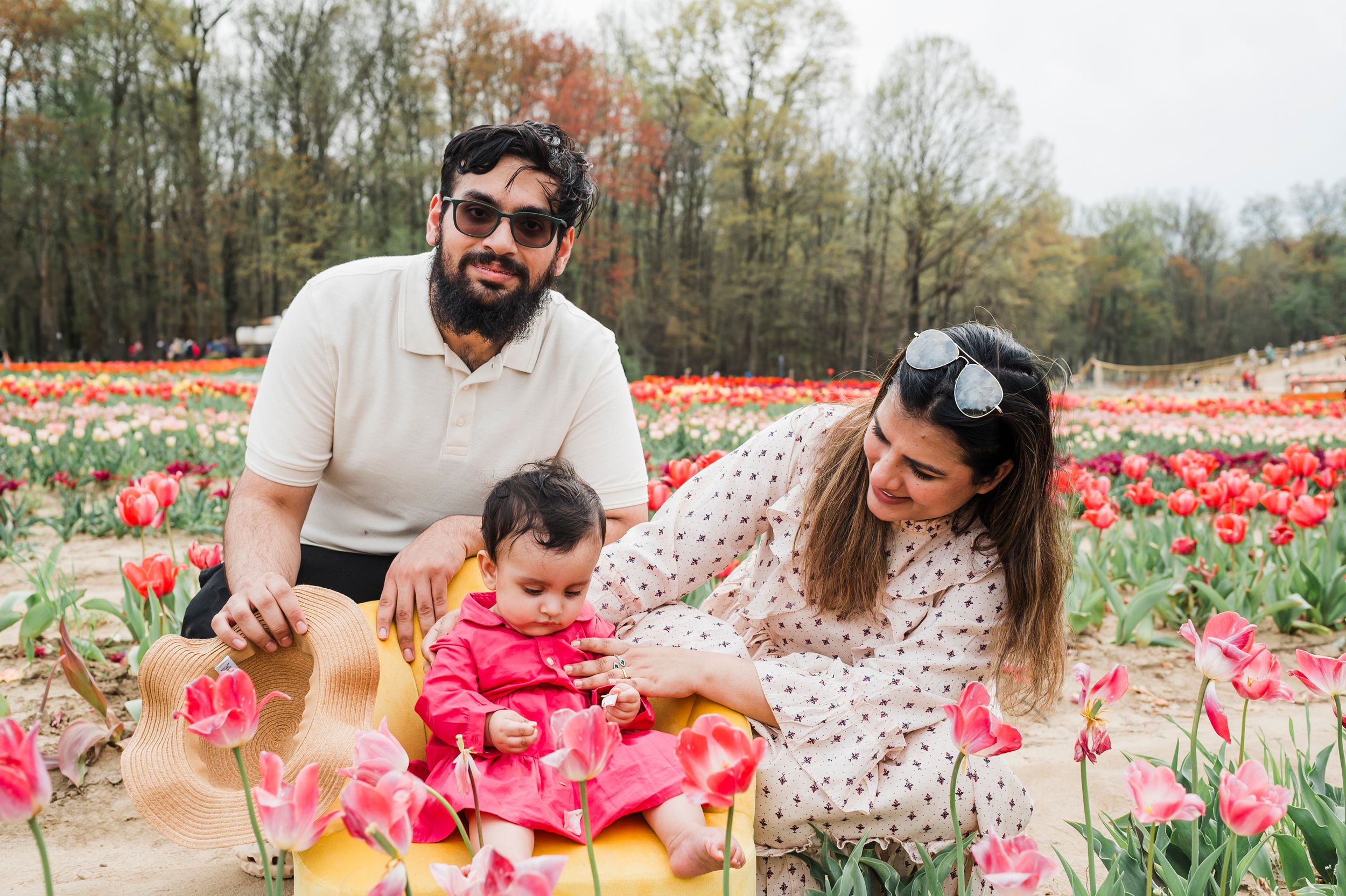 Family enjoying a spring day together in a vibrant tulip field with colorful red flowers blooming all around them.