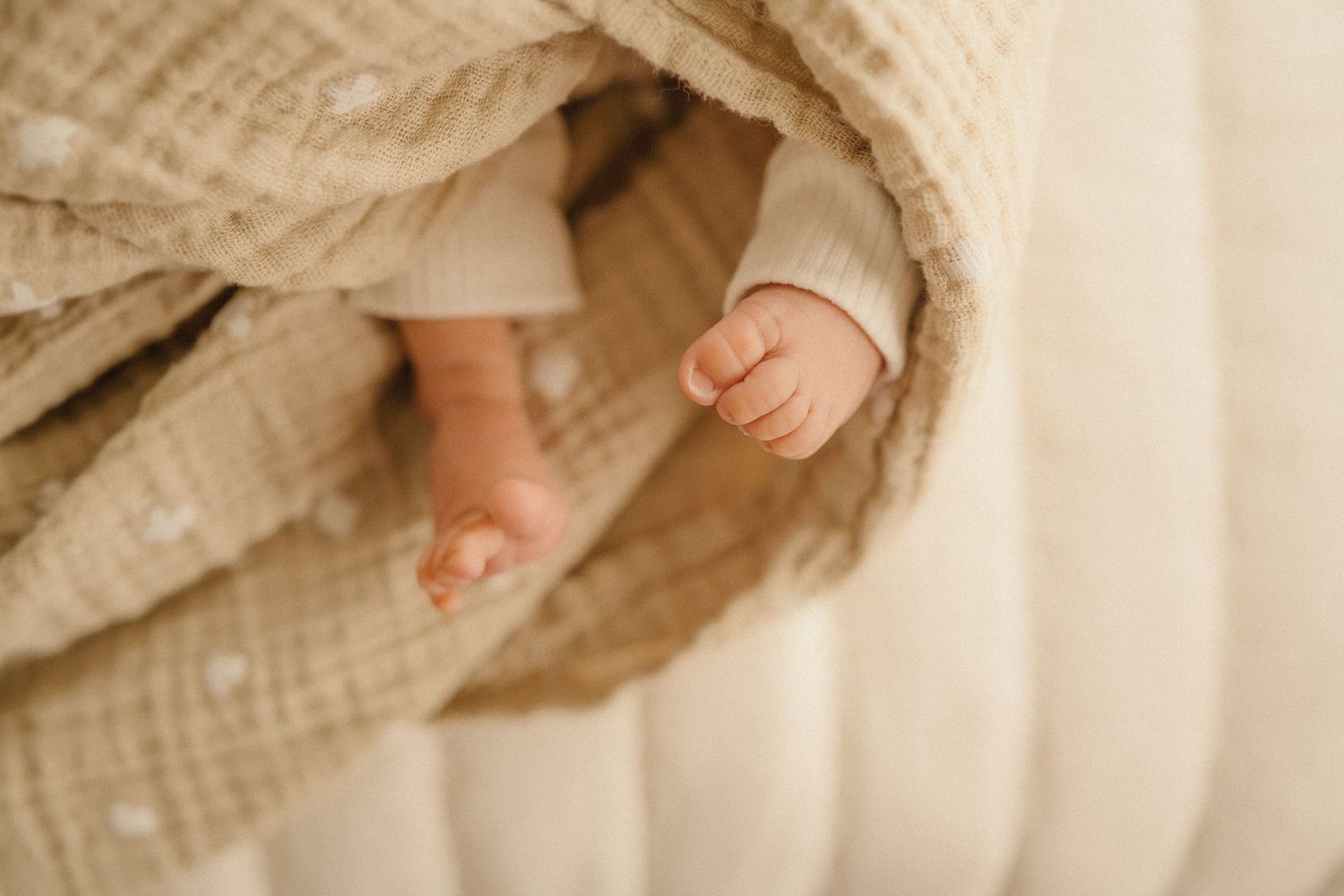Three sets of hands gently touching and embracing against the backdrop of off-white fabric.