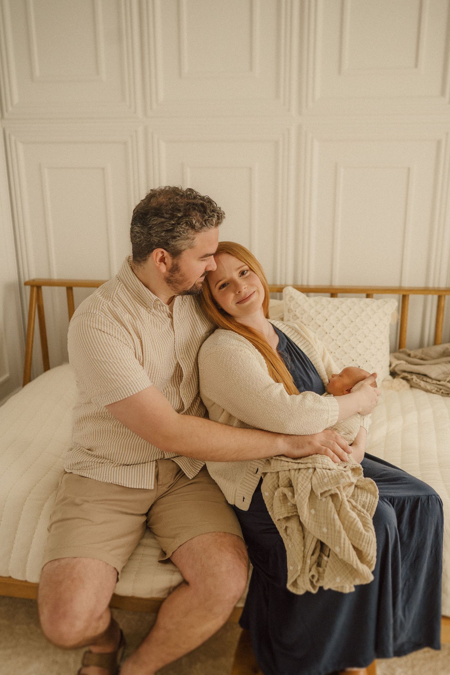 Couple sharing an intimate moment while cuddling on a white couch in a cozy living room setting.