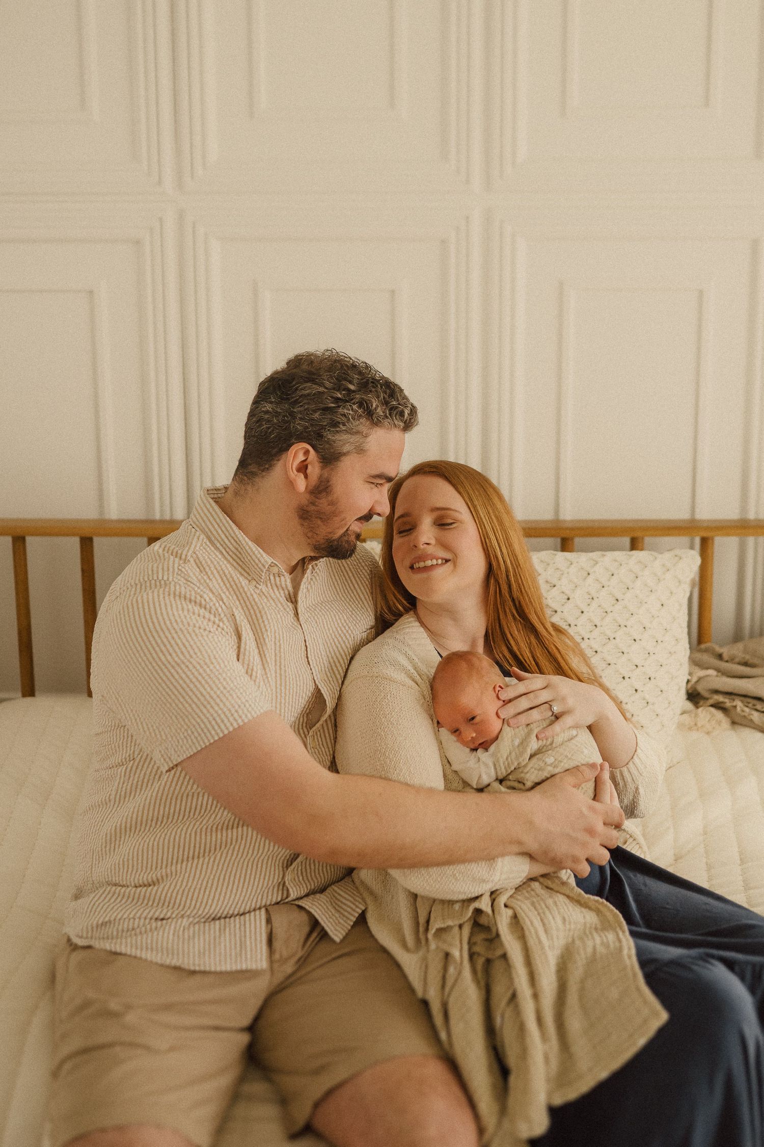 Intimate couple sharing tender moments together on a beige couch in a minimalist white room.