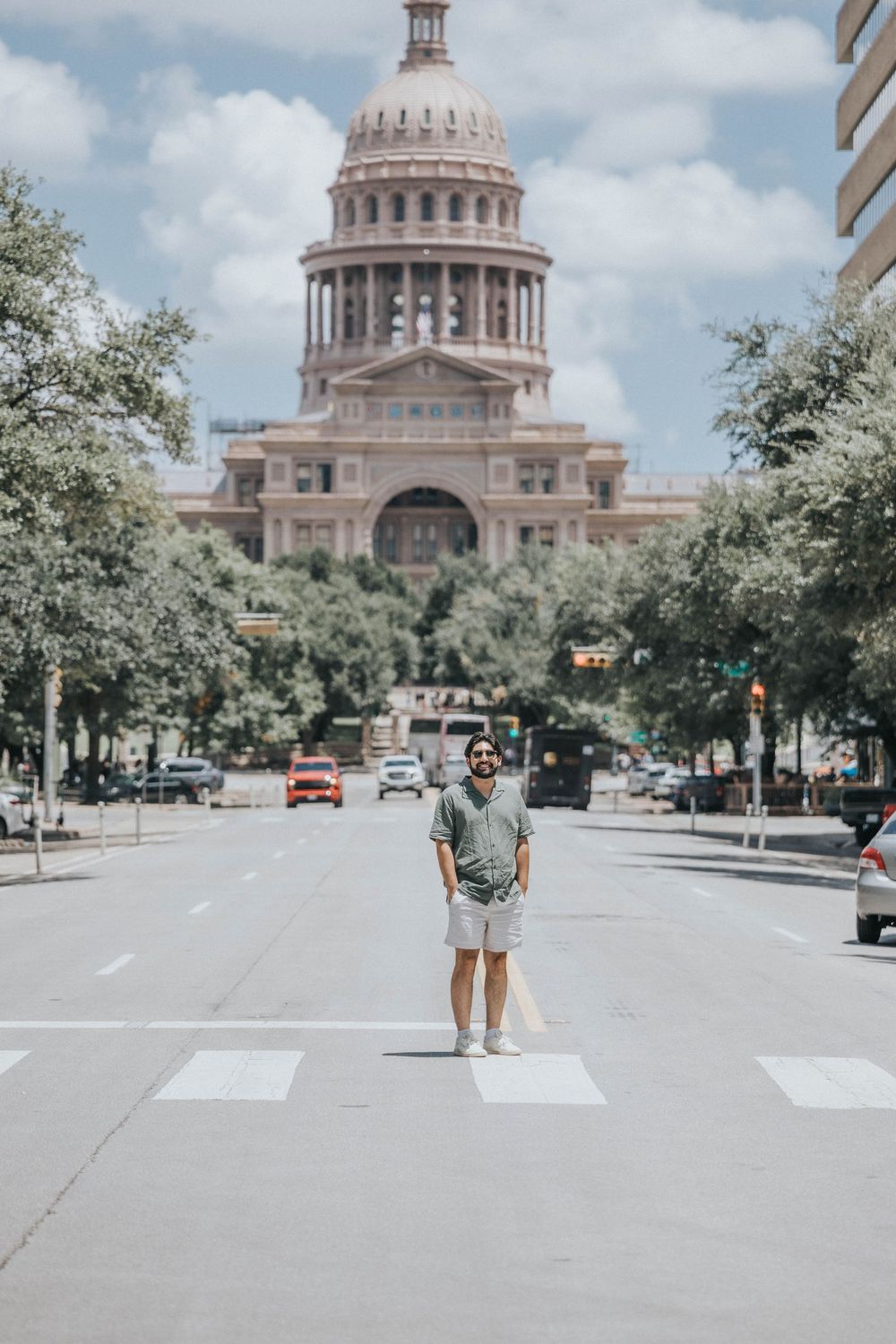 View of the Texas State Capitol dome and grounds on a sunny day with white clouds in the sky.