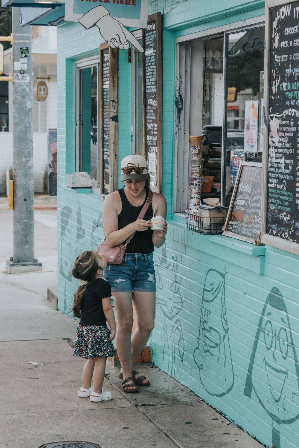 Street scene with turquoise-painted storefronts and people browsing outside local shops.
