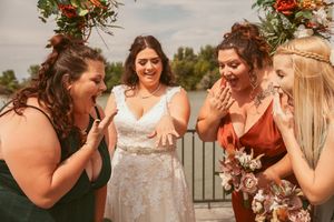 Joyful reaction shot of bridal party on waterfront deck during wedding celebration.