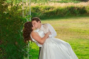 Romantic dip kiss in garden setting during outdoor wedding.