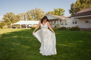 A flowing white wedding dress twirls against green grass during outdoor photography session.