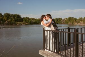 Romantic couple sharing an intimate moment on a lakeside wooden deck with scenic water views.