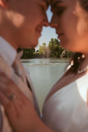 A romantic wedding photo silhouette with a fountain and lake in the background on a sunny day.