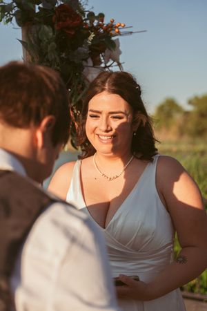 Two people share intimate moments during their wedding ceremony under blue skies.
