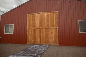 Large red barn with wooden sliding doors and two windows on exterior wall.
