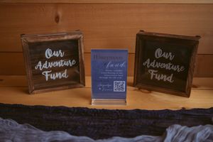 Rustic wooden decorative signs arranged on a shelf displaying text about adventures and memories.