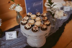 Chocolate and vanilla cupcakes arranged on a white pedestal cake stand at a dessert table.