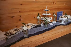 Dessert table setup with multiple tiers of treats displayed on rustic wooden boards against pine wall.