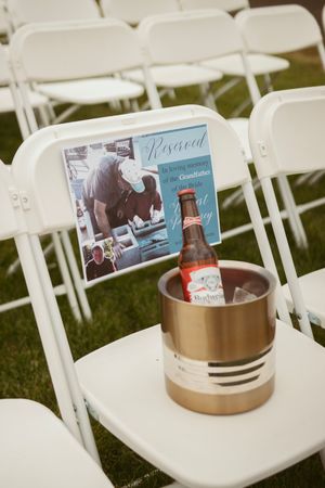 White folding chairs arranged outdoors with personalized photos and memorabilia on each seat.