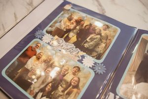 Wedding photo album spread showing vintage family photographs laid out on marble surface.