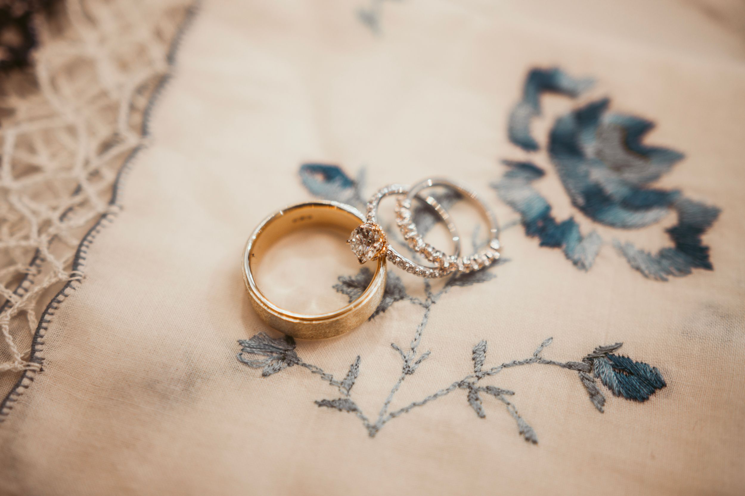 Metallic gold wedding bands resting on delicate blue butterfly pattern paper with floral motifs in vintage style.