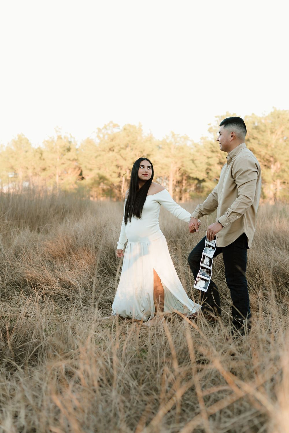 Couple dancing and twirling in golden field at sunset.