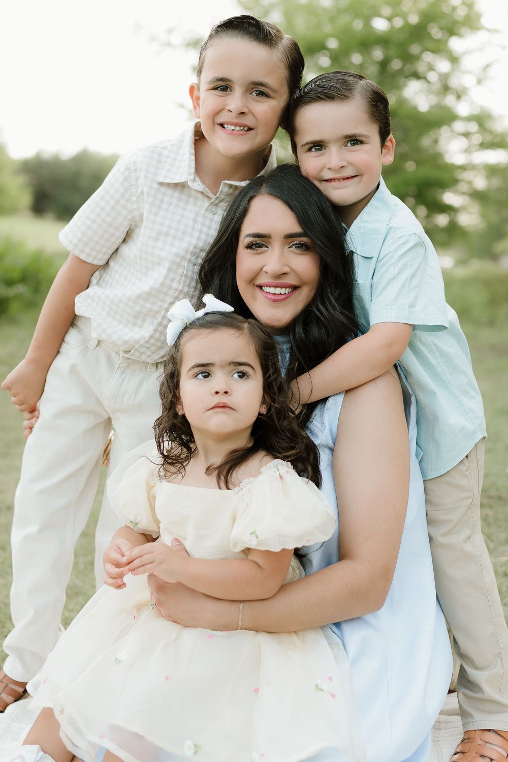 Family group wearing coordinating white and blue outfits embracing outdoors.