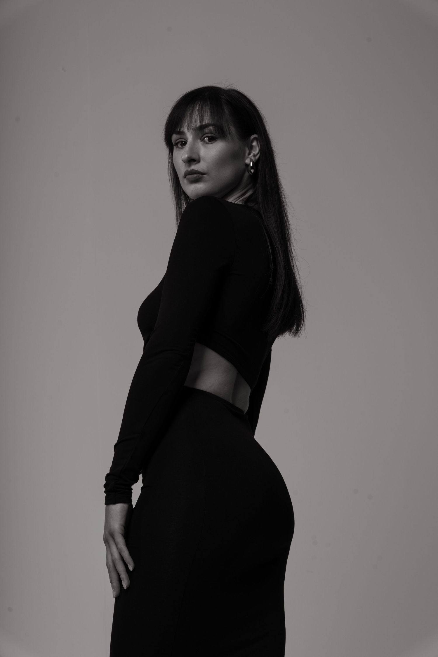 Portret kobiety z czarnymi włosami — elegancka modelka w czarnej sukience pozująca w studio