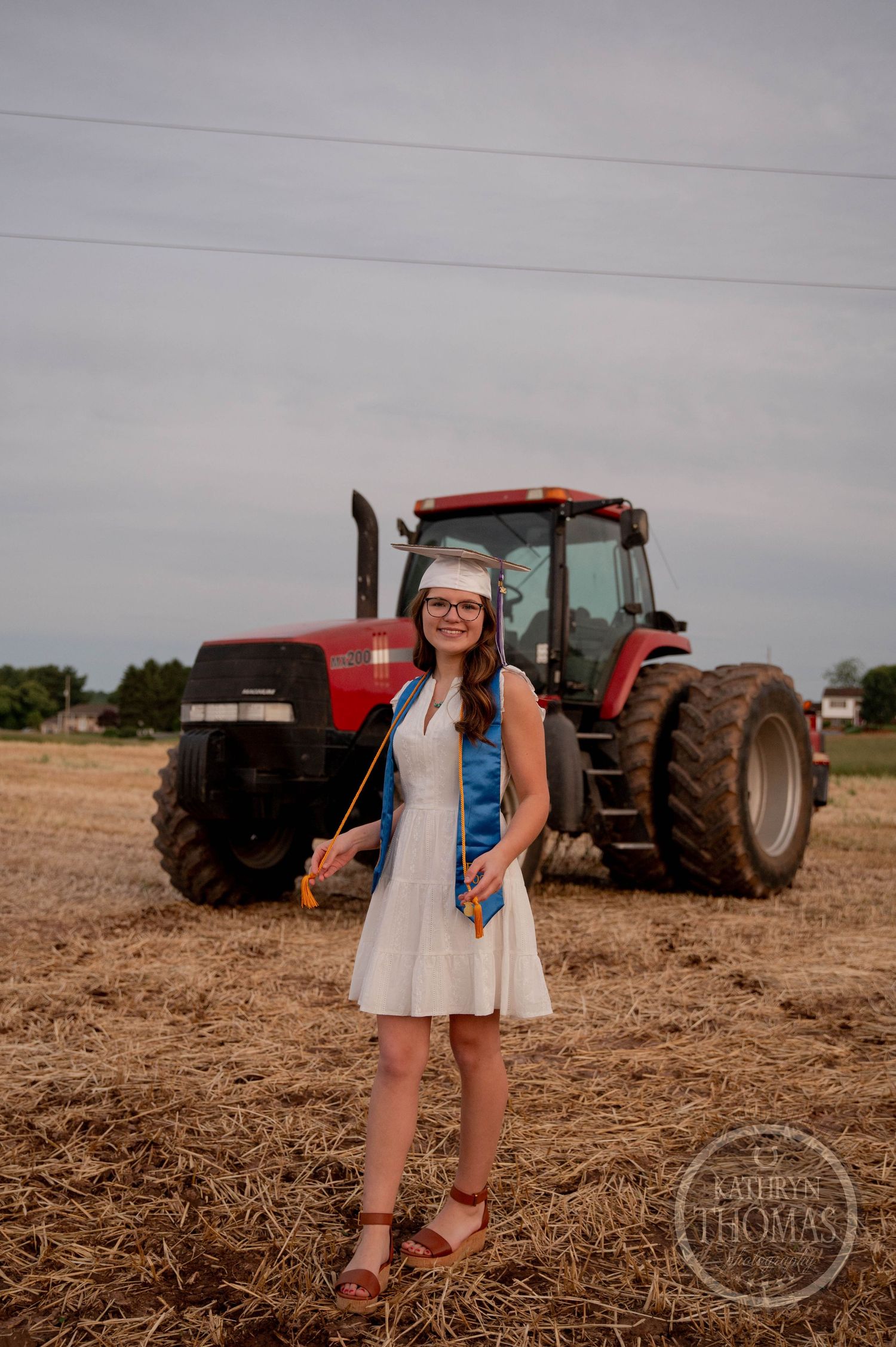 Standing in a field at sunset with a large red Case IH tractor in the background.