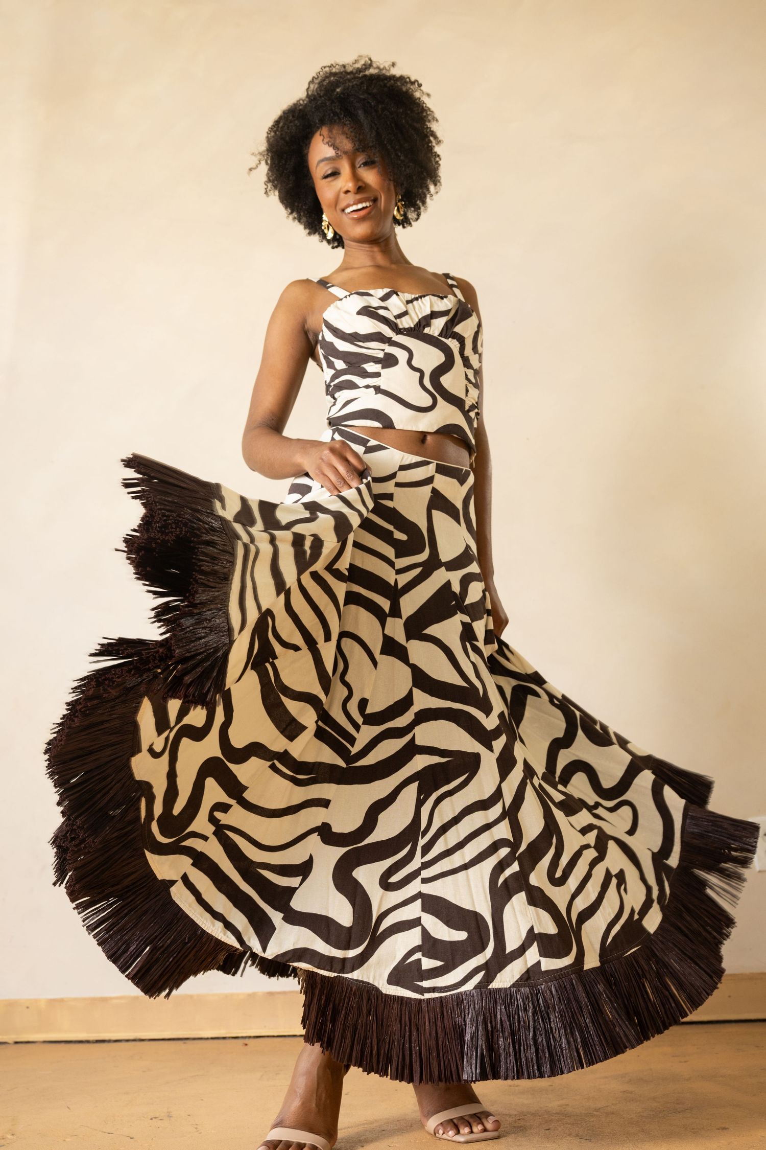 A flowing zebra print dress with black ruffled hem twirls in an energetic fashion photo series against a neutral backdrop.