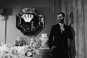 A black and white wedding reception photo showing guests at an elegant venue with floral arrangements and decorative mirrors.