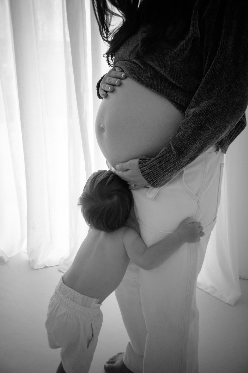 Black and white intimate maternity photos by window light.