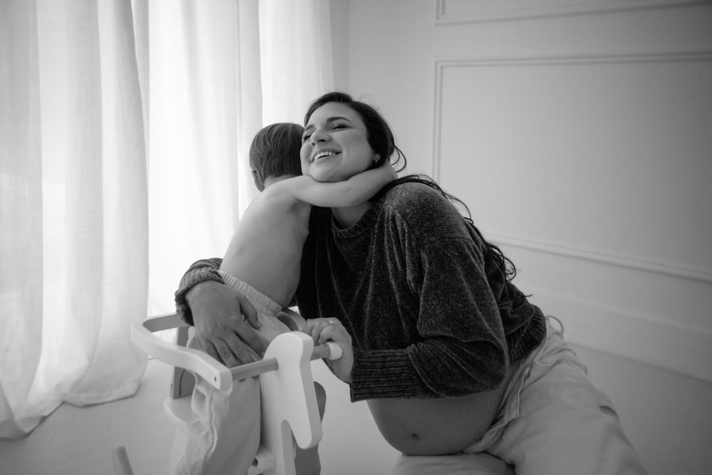 A tender black and white moment captured between parent and child by a window.