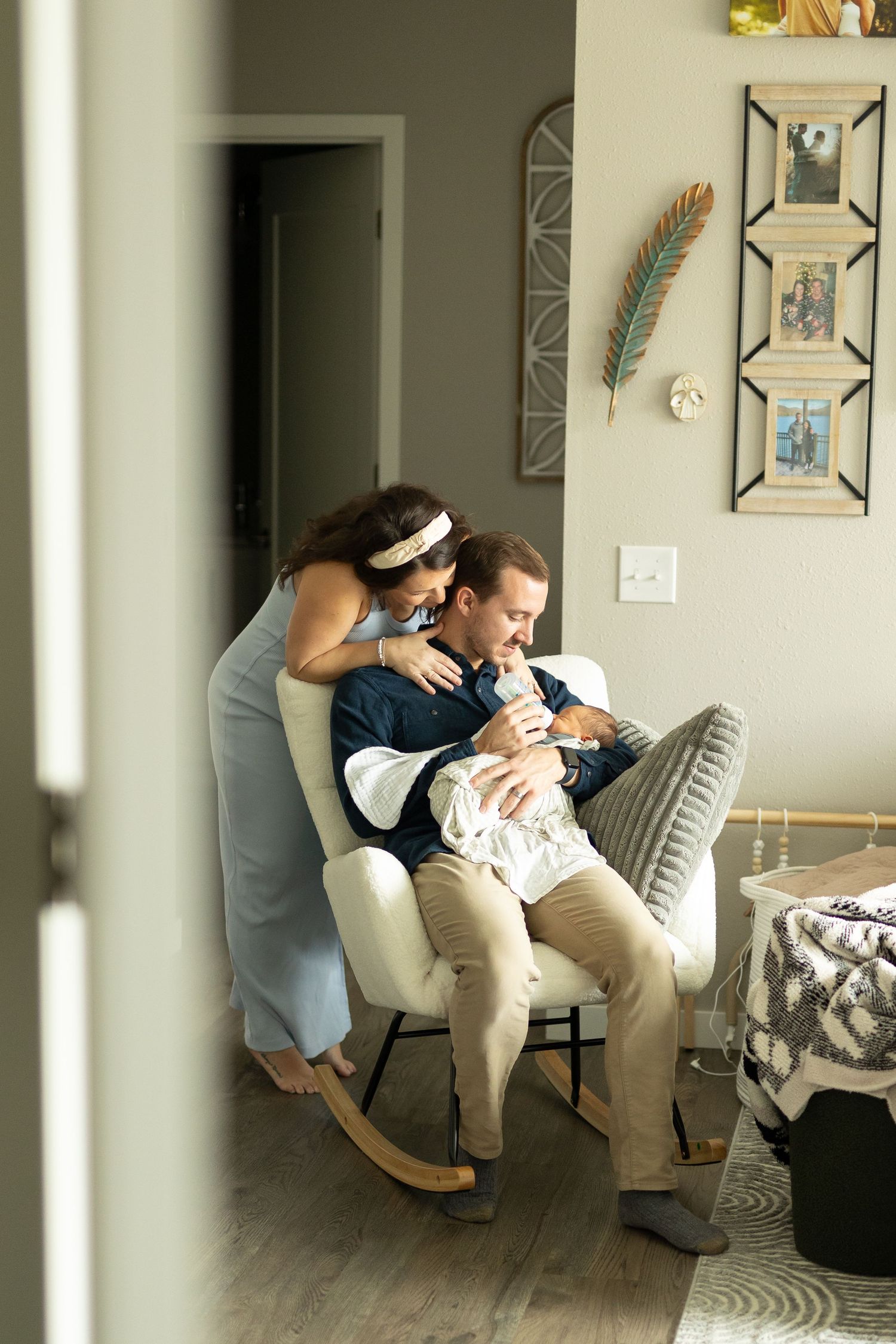 Proud parents looking down on their baby as the father rocks him in a chair