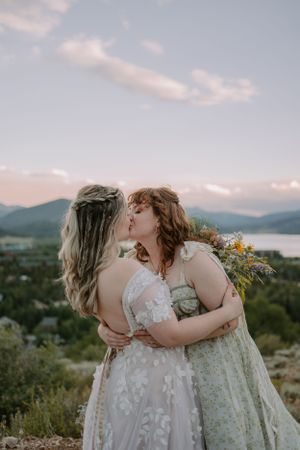 Closeup of white LGBTQ+ brides kissing on a mountain trail in Colorado.
