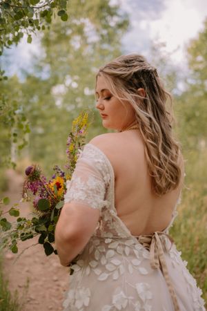 Victoria, a white bride with blonde hair, looking back over her shoulder, her long white dress flowing out behind her.