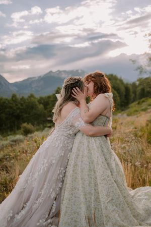 LGBTQ+ brides embrace and kiss on a mountain trail in Silverthorne, Colorado.