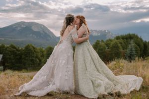 Emma and Victoria embrace and kiss on a mountain trail in Silverthorne, Colorado.