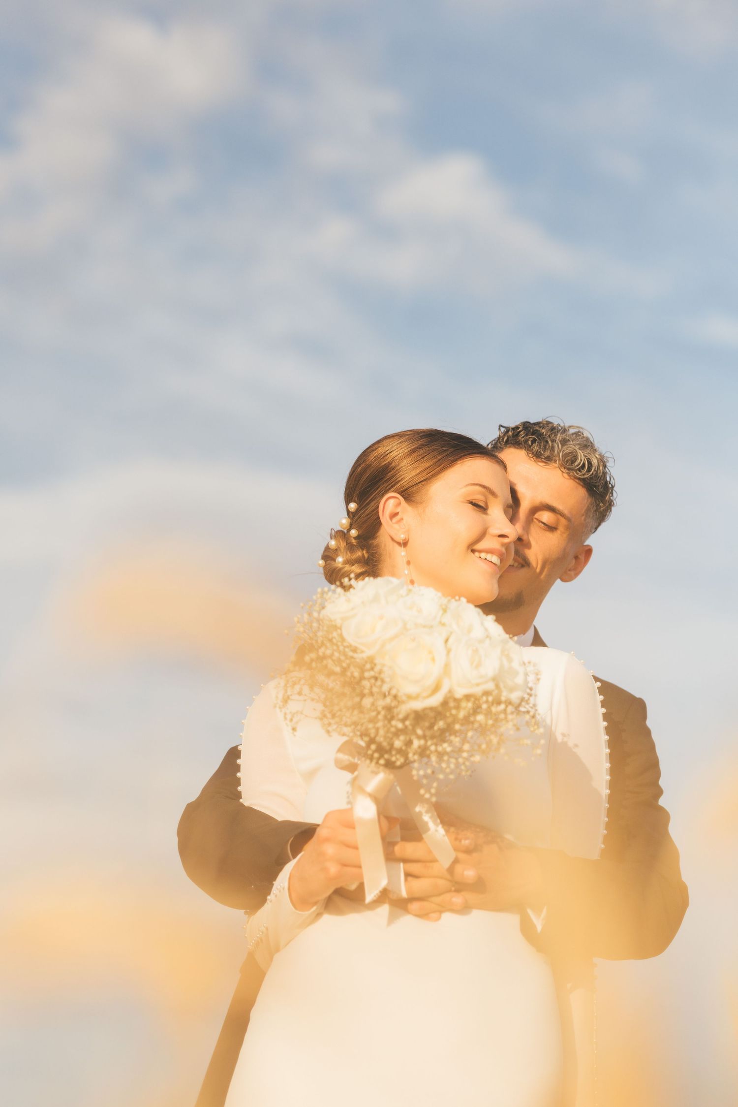 A romantic black and white panorama of a couple embracing during a wedding photoshoot outdoors.