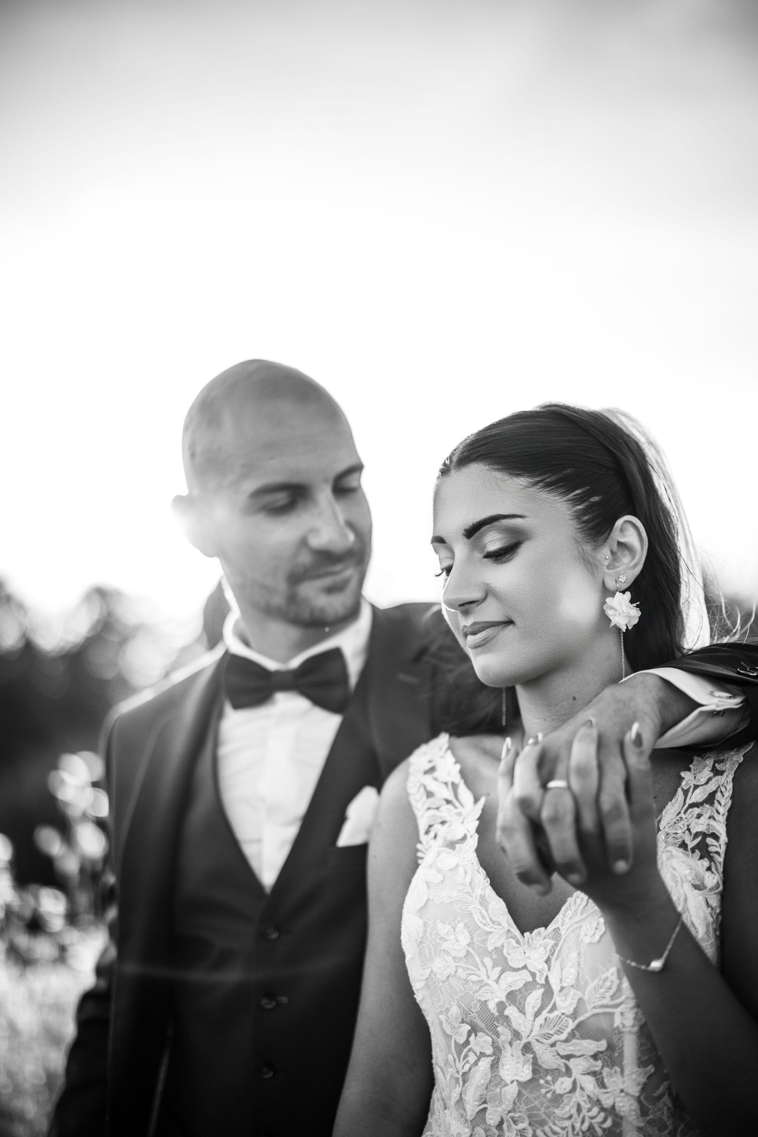 A romantic black and white panorama of a couple embracing during a wedding photoshoot outdoors.