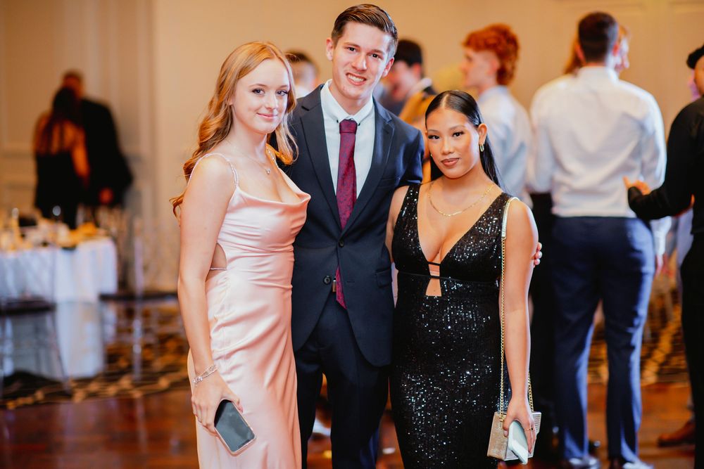 Wedding reception guests dancing and mingling in an elegant ballroom with warm lighting and formal attire.
