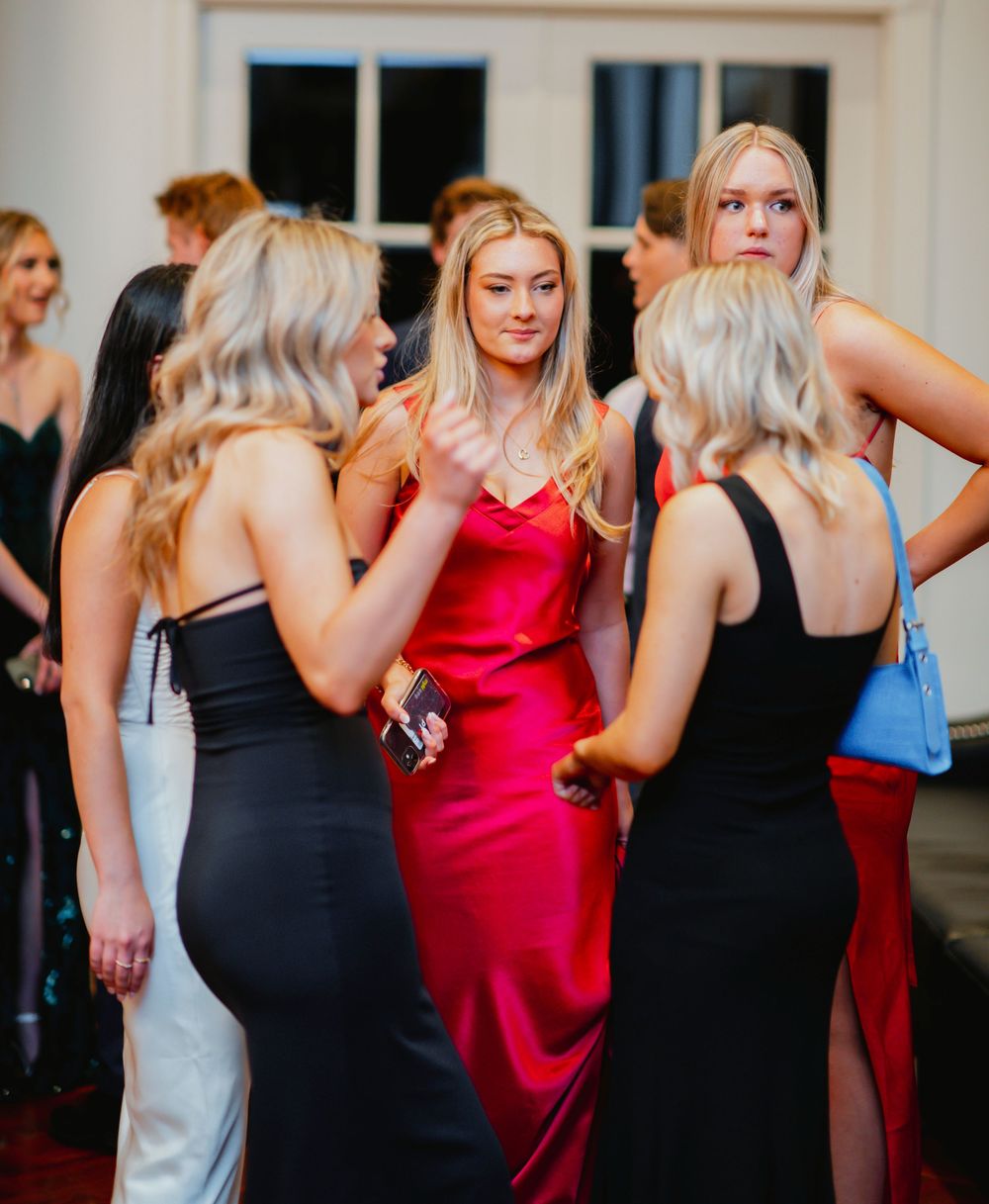 Group of women in formal attire dancing and celebrating at an elegant indoor party or reception.