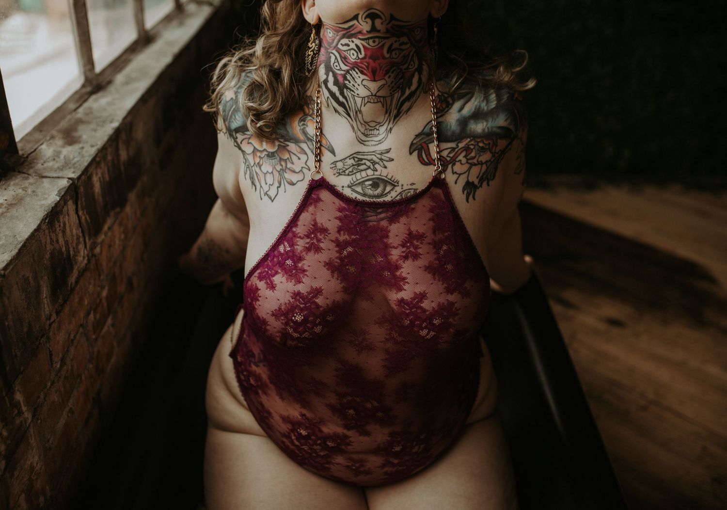 Burgundy velvet floral one-piece bodysuit on wooden floor with soft natural lighting.
