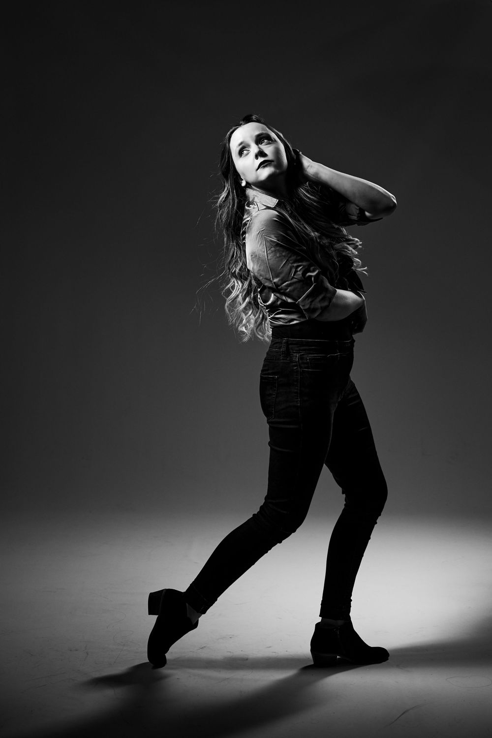 Black and white photo sequence shows dramatic dance movements with figure twirling from left to right on dark stage.